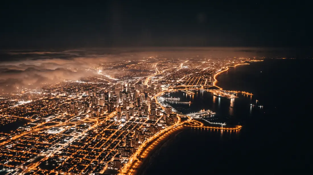 Ciudad costera de noche desde el avión en descenso
